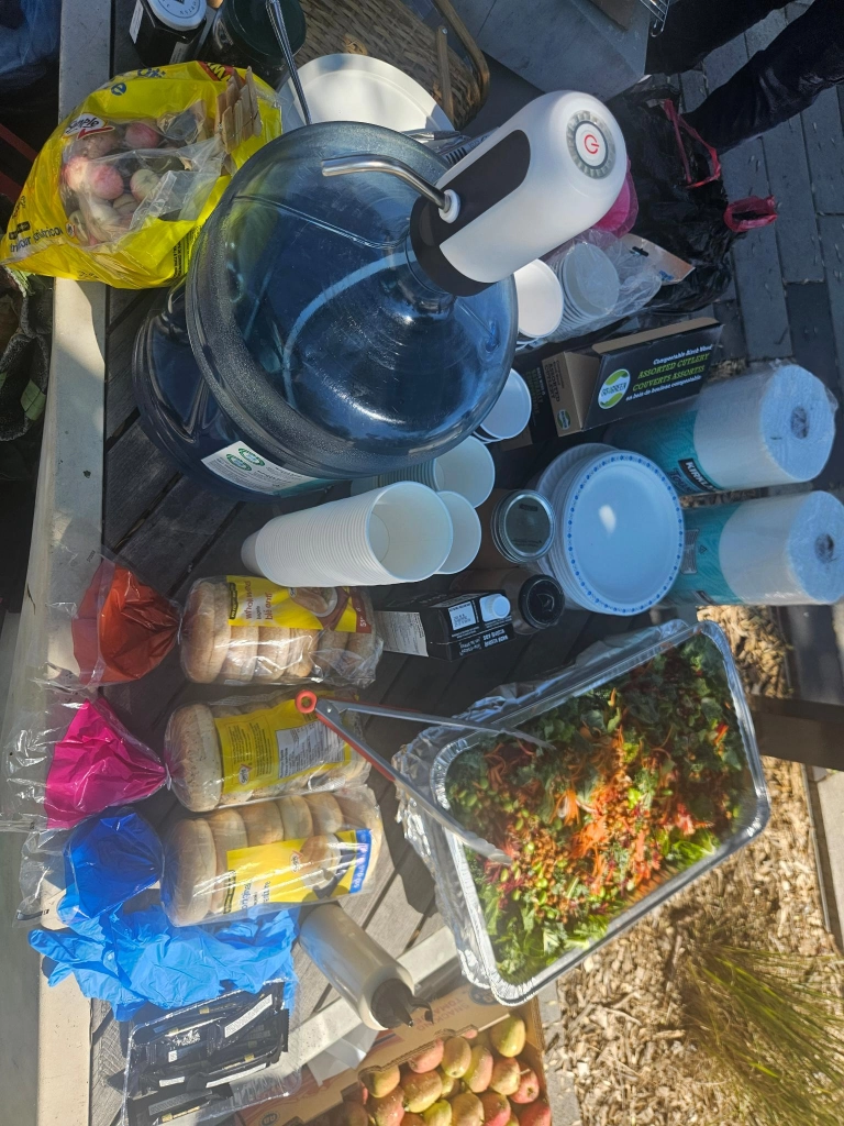 Table with a
                             water jug, bagels, crab apples, and salad set out