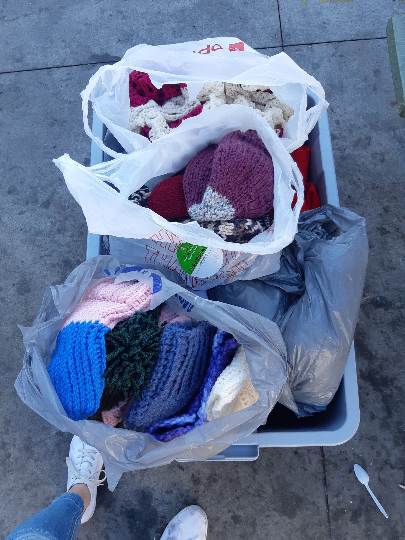 Grocery bag filled with hand knitted mittens and toques.